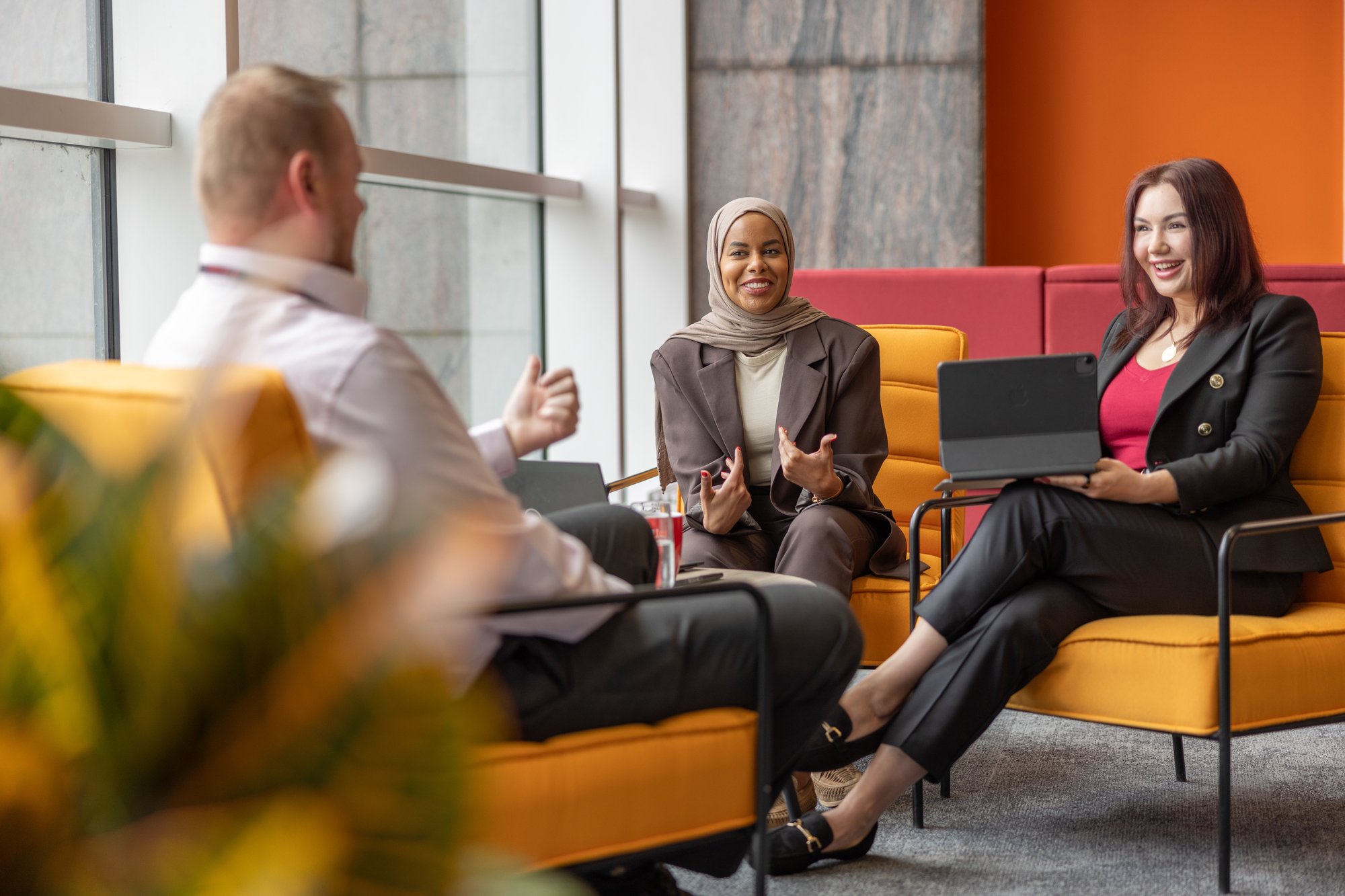 Two women and man on orange seats meeting 2